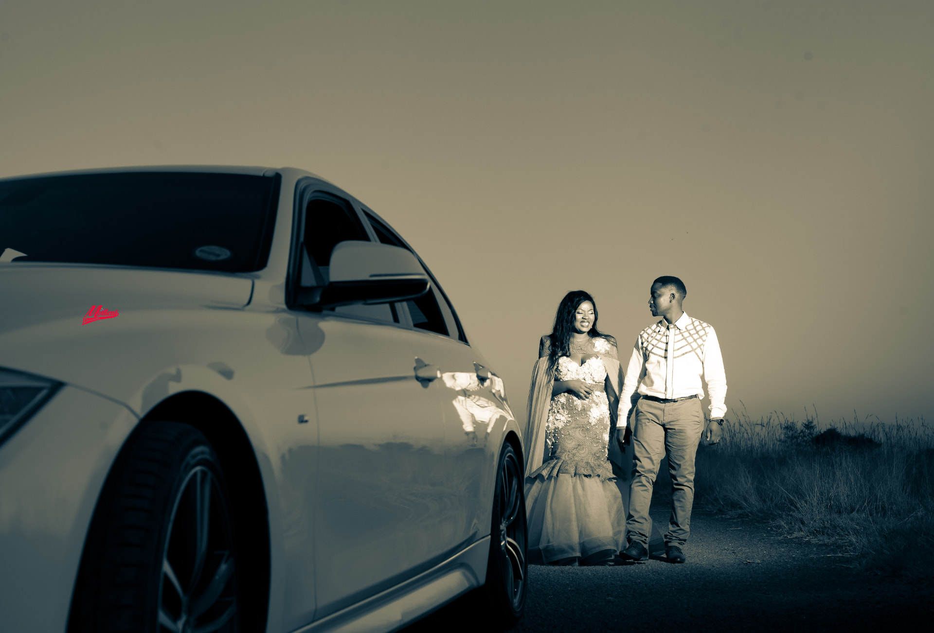 Toned location portrait of a couple beside a car at dusk